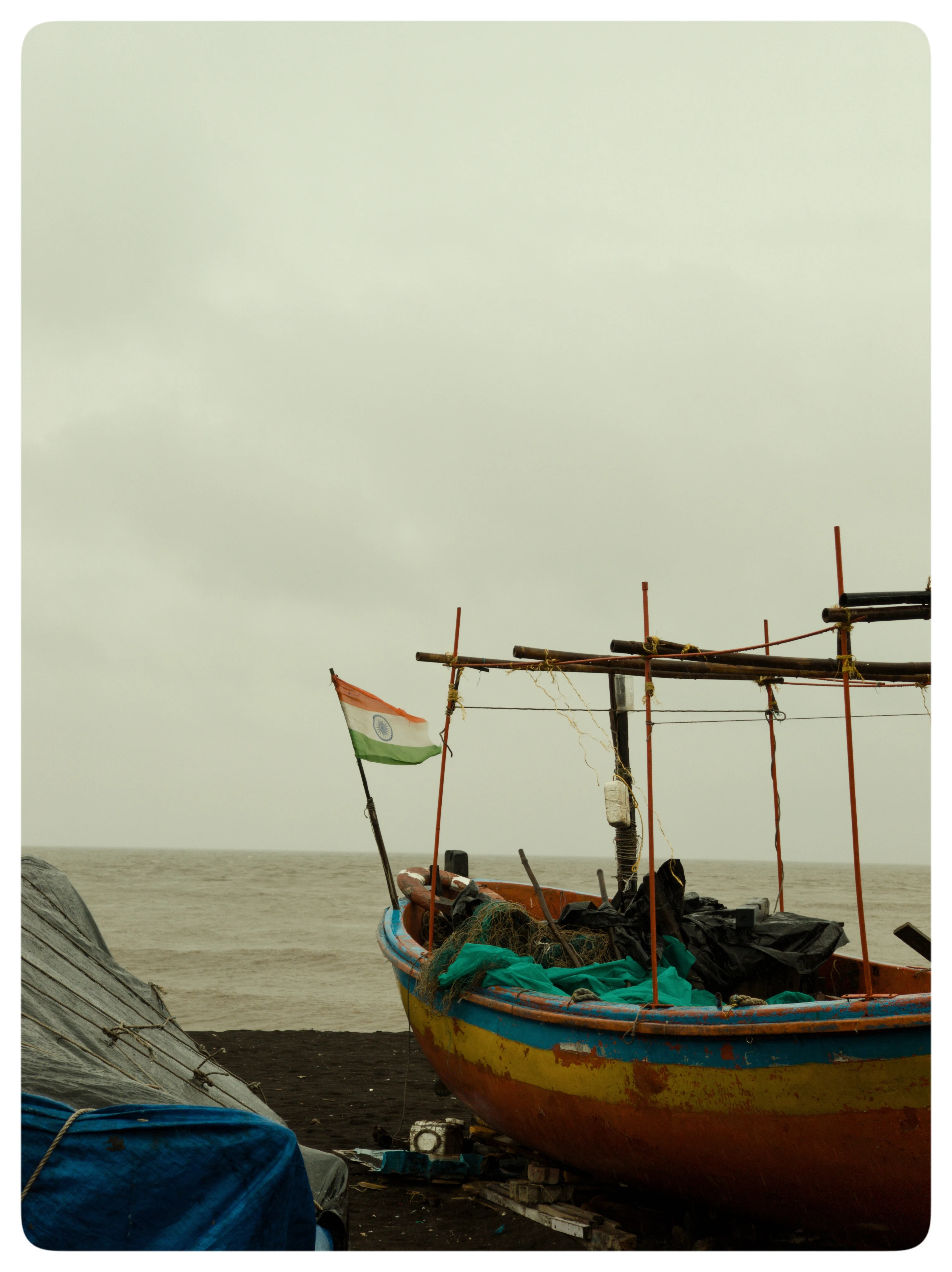 A colourful fishing boat with bamboo rigging rests beside the water.