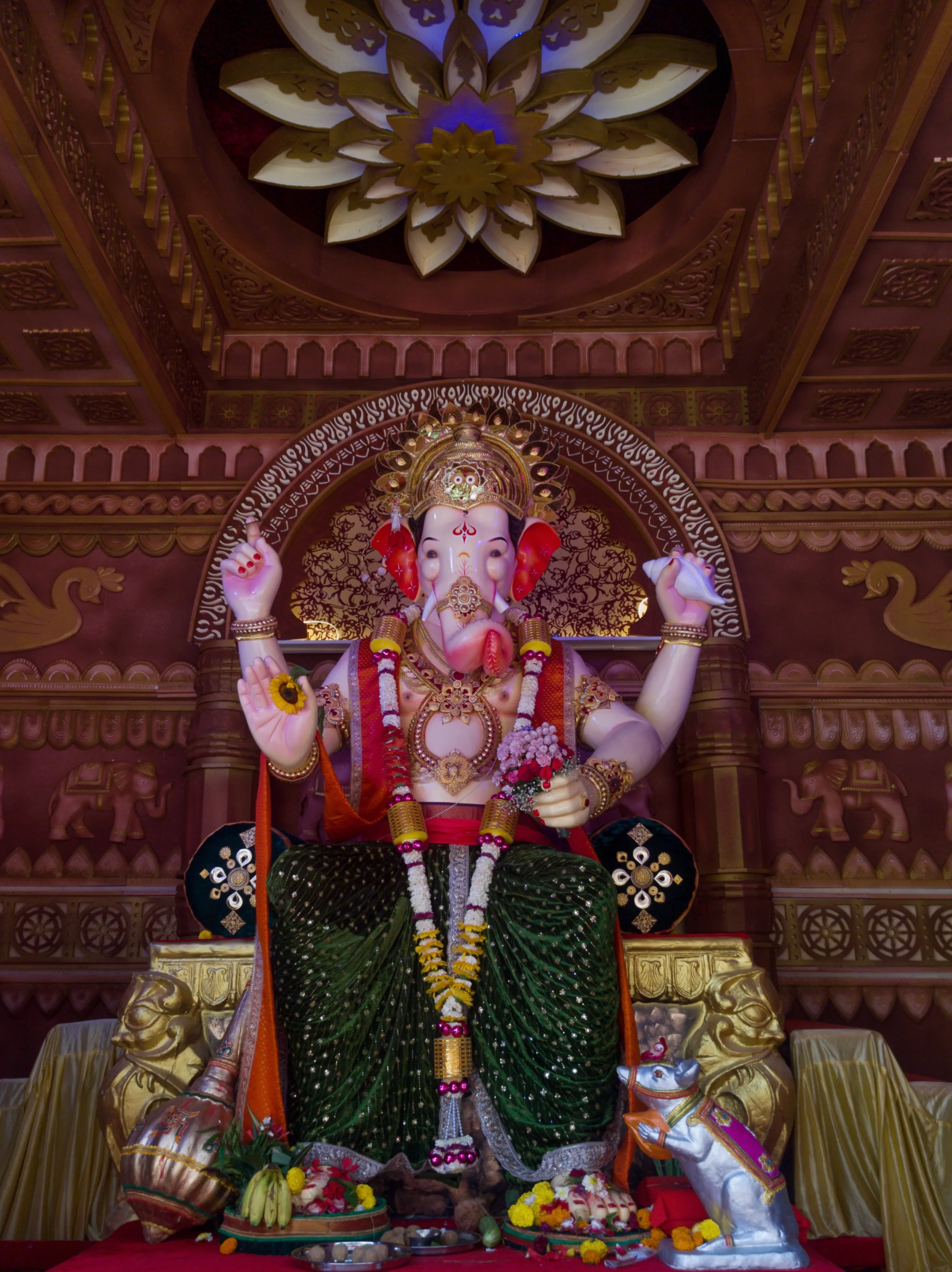 A decorated Ganesha altar beneath a richly carved wooden ceiling.