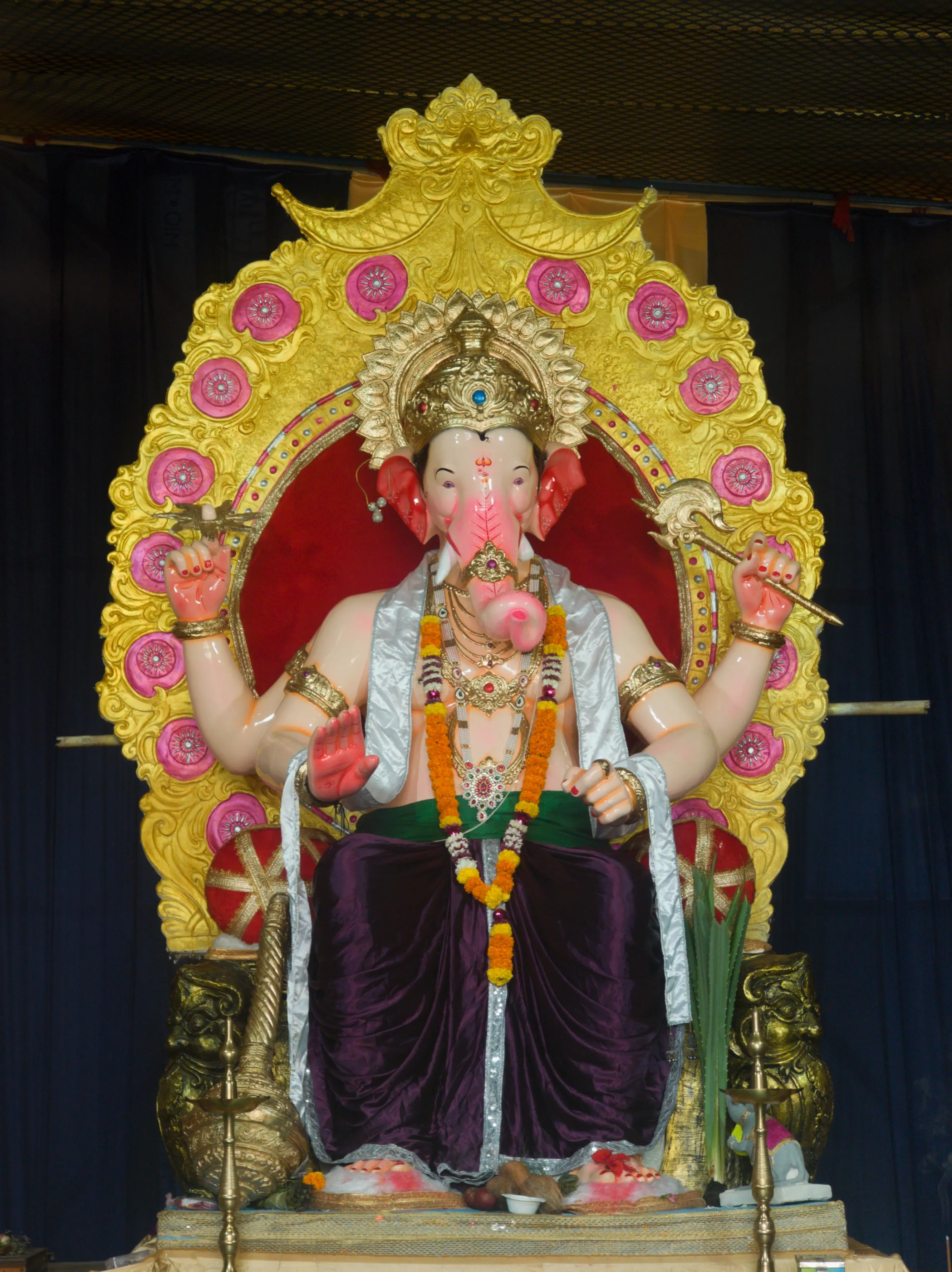 A Ganesha idol with flower garlands framed by a large yellow decorative halo.